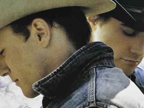 Close up of a poster for Brokeback Mountain. Heath Ledger and Jake Gyllenhaal are pictured standing in profile. Both men are looking down away from one another.