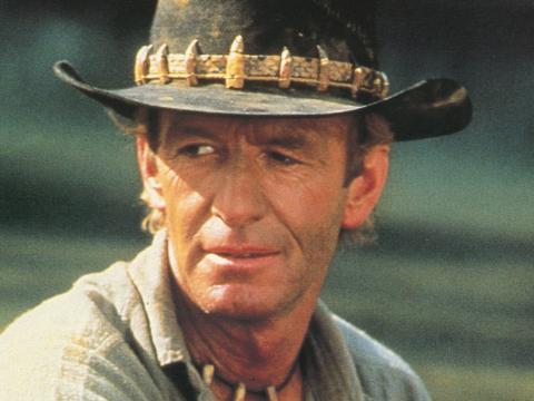 Paul Hogan wearing his famous akubra hat looking off-camera in a still from Crocodile Dundee