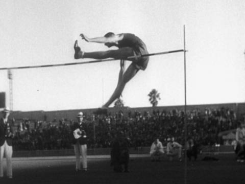Black and white photo of a high jumper leaping over the bar