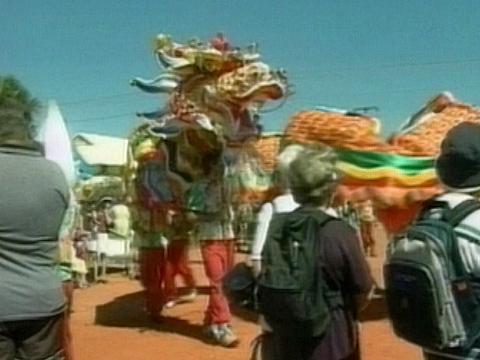 Chinese dragon performance in the screen as people look on. 