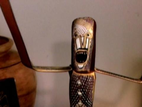 A anthropomorphised sculpture with a face is screaming and holding arms out to the side
