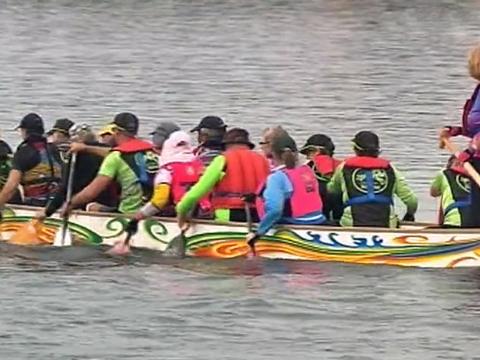 A group of people rowing a dragon boat on a river.