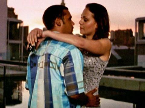 A man and woman embracing on a rooftop during sunset