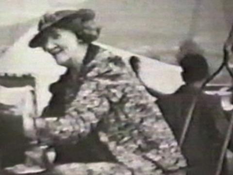 A woman dressed in a hat, coat and gloves is riding on a fairground ride at a show.