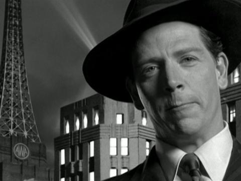 Close up of Rupert Kathner (Ben Mendelsohn) with buildings behind