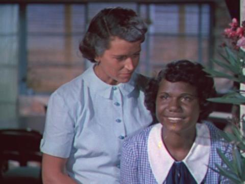 Jedda (Ngarla Kunoth) stares dreamily out a window with her adoptive mother (Betty Suttor) behind her