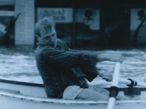Chris (Chris Haywood) rowing through the floodwaters of Maitland