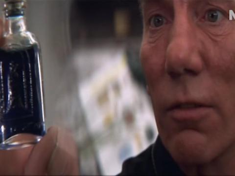 Close up of Father Laurence (Pete Postlethwaite) holding a small bottle of blue liquid