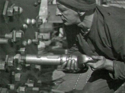 Black and white image of a construction worker riveting a chord joint in the construction of the Sydney Harbour Bridge