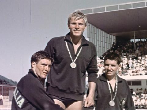 Australian swiimer Muray Rose stands on the winning podium with the place-getters either side of him.