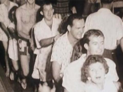 People wearing pyjamas form a conga line at a party.