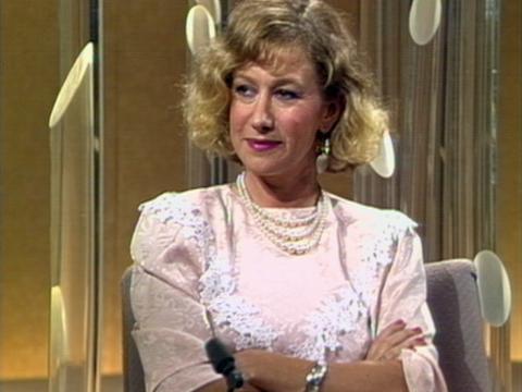 Actress Helen Mirren sits with her arms folded. She's in a studio.