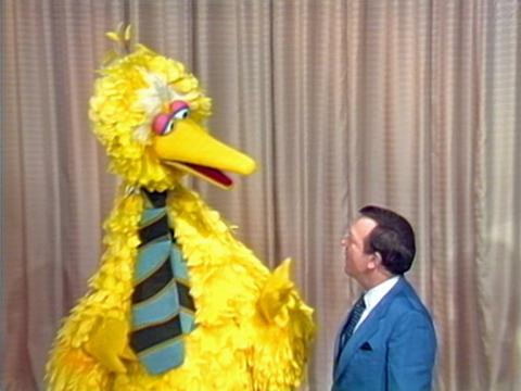 Giant yellow bird puppet - Big Bird - talking with Mike Walsh. Both of them are wearing ties.