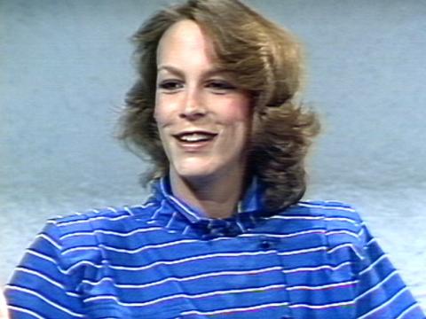 Actress Jamie Lee Curtis smiles as she speaks. She is sitting in a studio. 