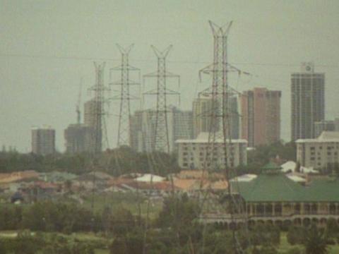 A smoggy cityscape with powerlines and skyscrapers.