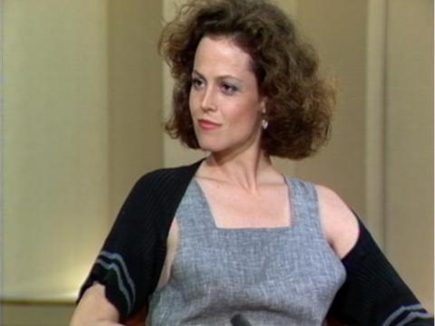 American actress Sigourney Weaver sits in a studio. She has a comanding look in her eyes.