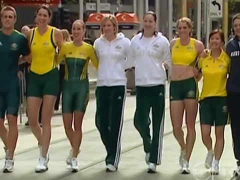 Eight Australian athletes walking arm in arm on a Melbourne street modeling the Commonwealth Games uniforms.