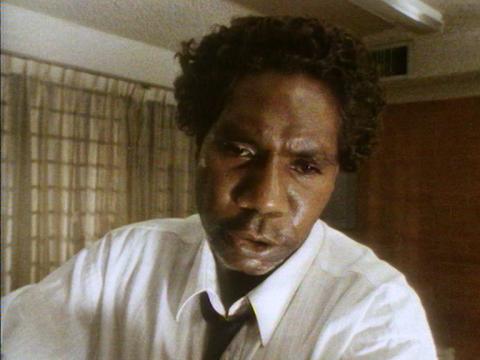 A man in a suit looks down at the camera