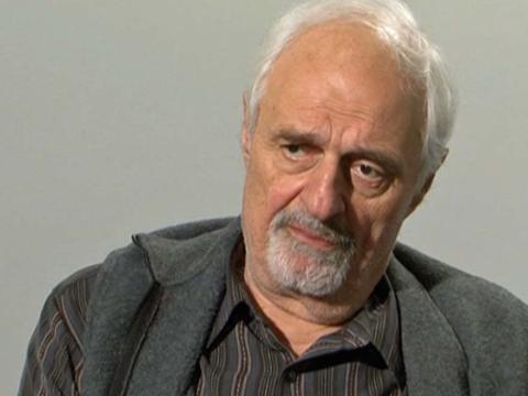 Ted Kotcheff in front of a grey background