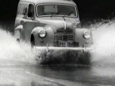A car driving through a flooded road in 1963