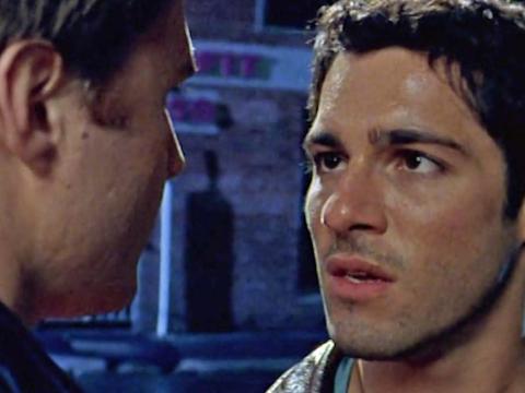 Two men talking close together on the street at night