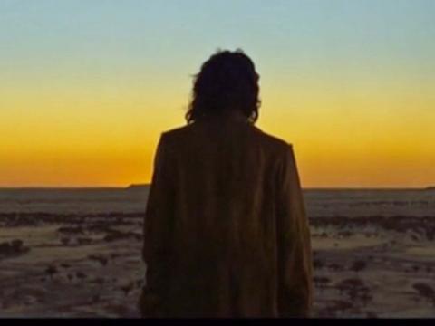 The figure of a man in an outback landscape silhouetted against a setting sun