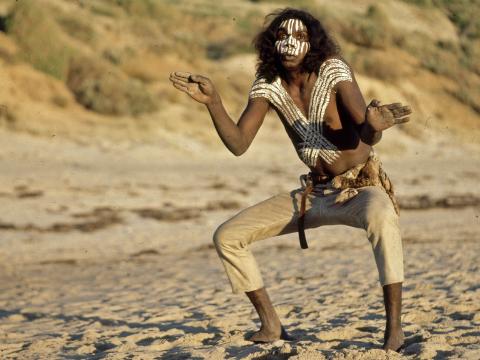 David Gulpilil as Fingerbone Bill in a dance pose while he's telling the story of the pelican on the beach in Storm Boy
