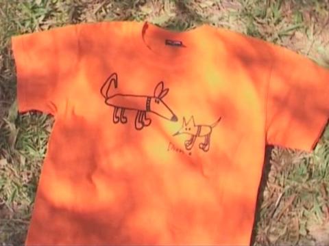 An orange t-shirt with one of Dion Beasley's drawings of dogs on it