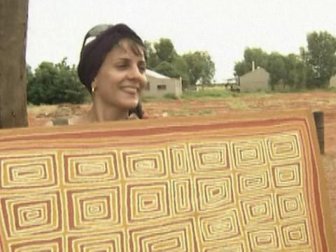 Erica Izett holds up an Aboriginal painting smiling