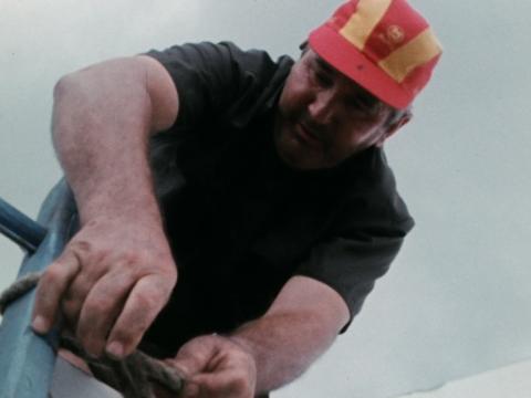 A man making repairs on a roof ripped apart by the cyclone
