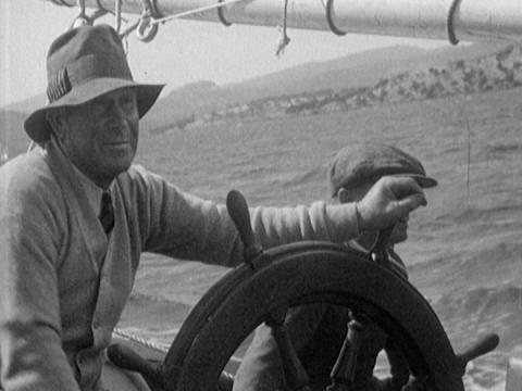 A man steers a sailing ship sailing along the Derwent River, Tasmania.