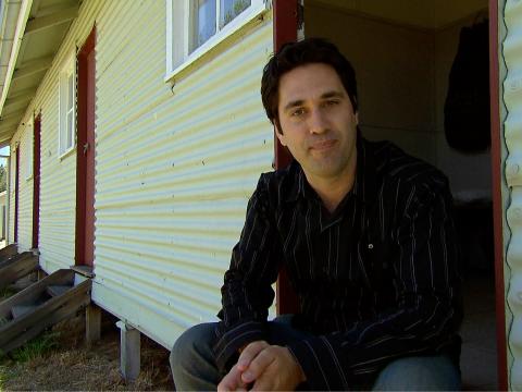 Man sitting on the doorstep of a dormitory housing barracks.