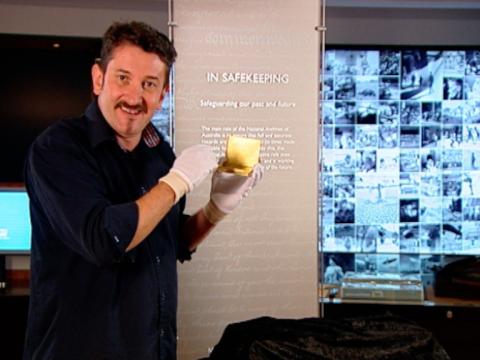 Warren Brown stands holding a gold cigarette case.