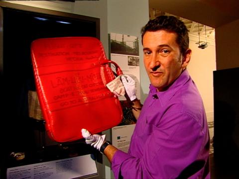 Warren Brown holds Cuc Lam's red suitcase.