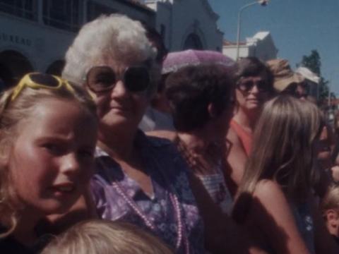Crowd shot of young and old watching a street parade.