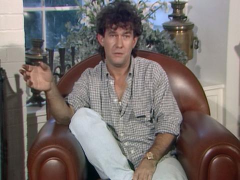 Jimmy Barnes sitting in a brown leather armchair talking to camera