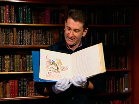 Warren Brown holds open the book 'The Magic Pudding'.