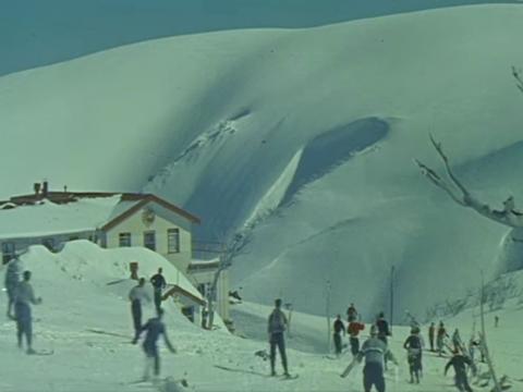 Snow field with skiers and chalet
