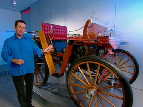 Warren Brown stands next to the open display of a vintage car.