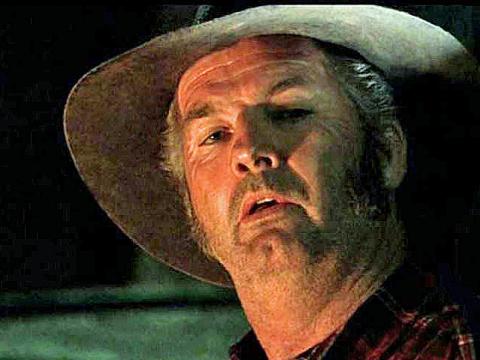 Close up of weather beaten man's face wearing a hat and looking distainful.