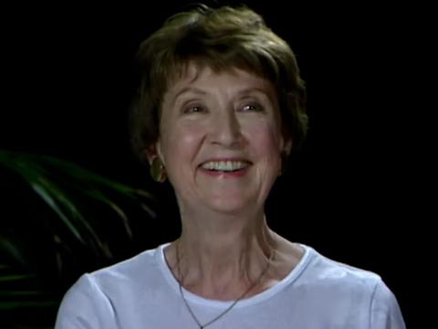Head and shoulders shot of a middle aged woman smiling.