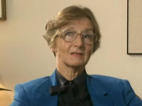 Head and shoulders shot of an older woman sitting looking at camera.