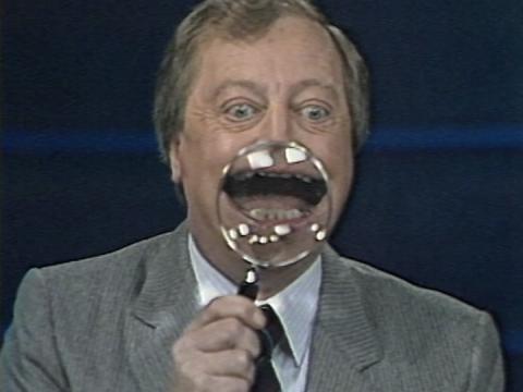 Graham Kennedy on the set of 11am with a magnifying glass over his open mouth