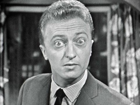 Black and white image of Graham Kennedy with eyes wide open in a comical way looking at camera