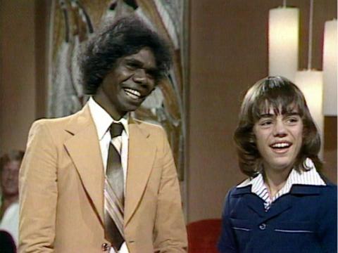 David Gulpilil and Greg Rowe in a television studio smiling together.
