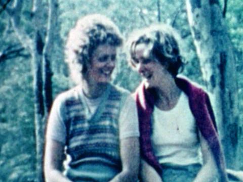 Two women sitting next to each other smiling