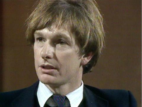 Peter Weir in a suit being interviewed.
