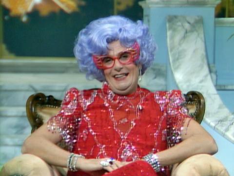 Dame Edna has a confiding look as she looks at the camera.