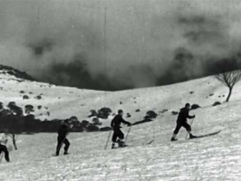 Four men on skis walking up a snowy mountain