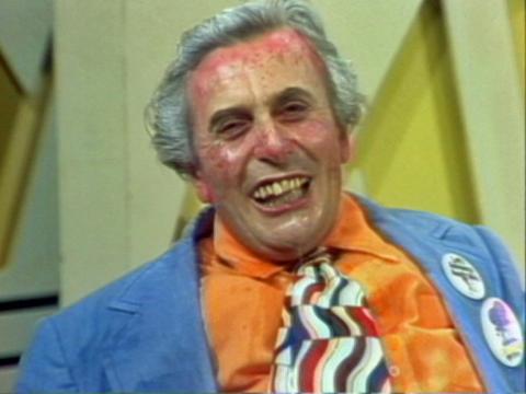 A mid-shot of Barry Humphries as Les Patterson. He is drooling and has a reddened face.